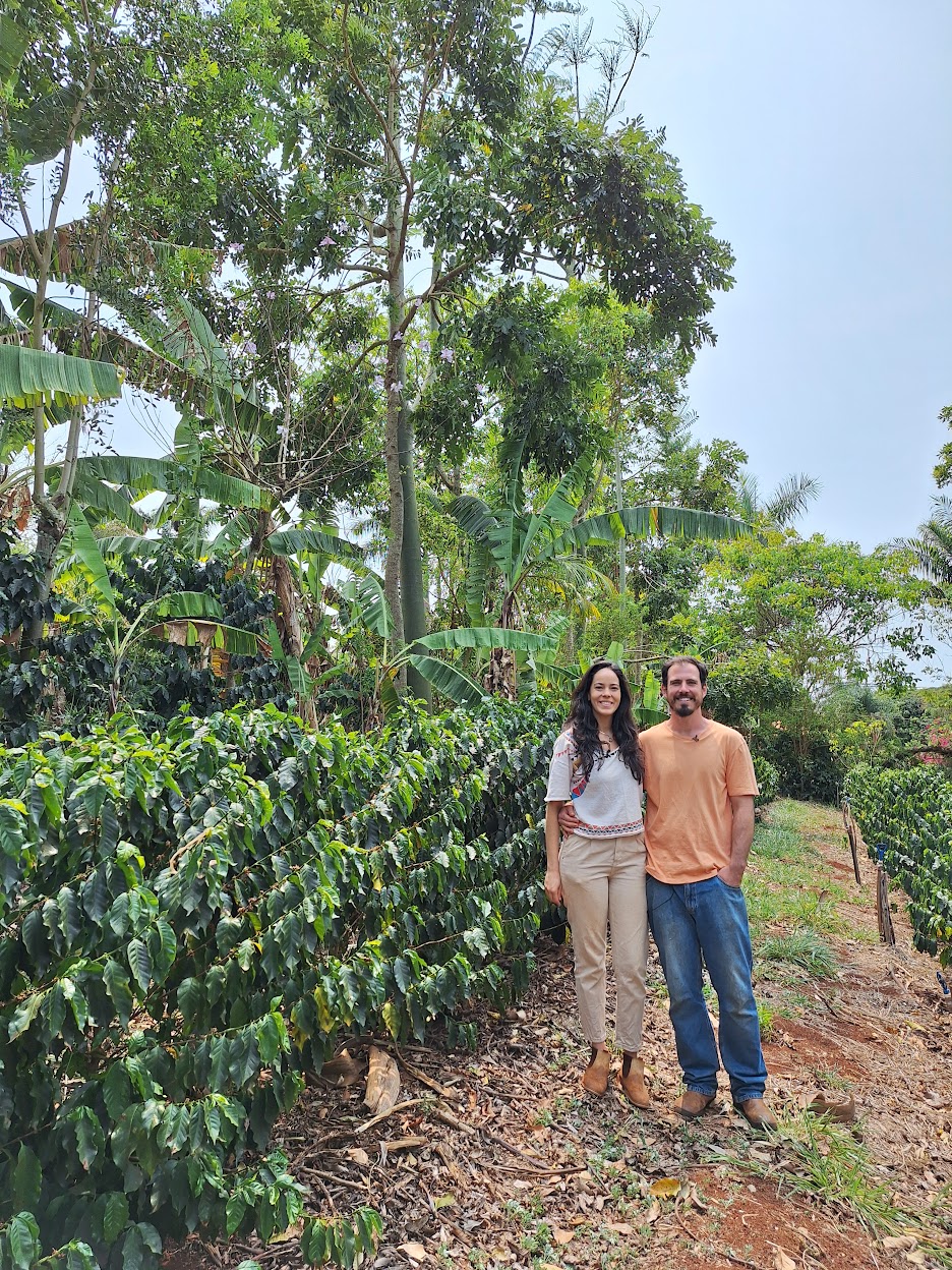 Cris e Pedro entre o cafezal e a agrofloresta do sítio